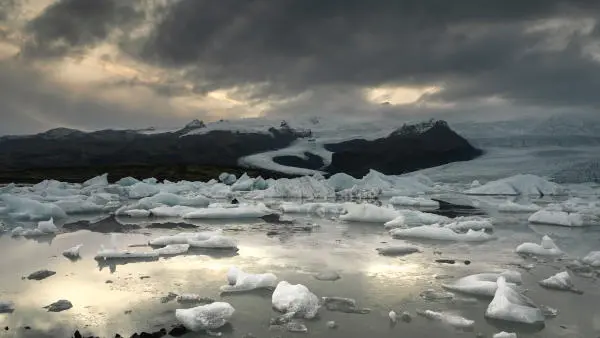 With a giant glacier in the background, the foreground is a glacier lake with hundreds of small icebergs. Picture taken during sunrise