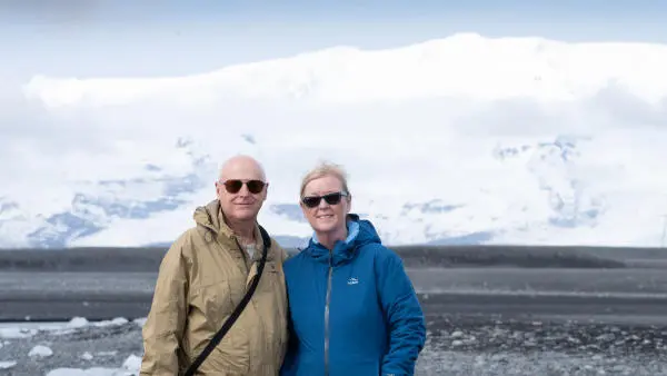 Two happy clients posing in front of a glacier