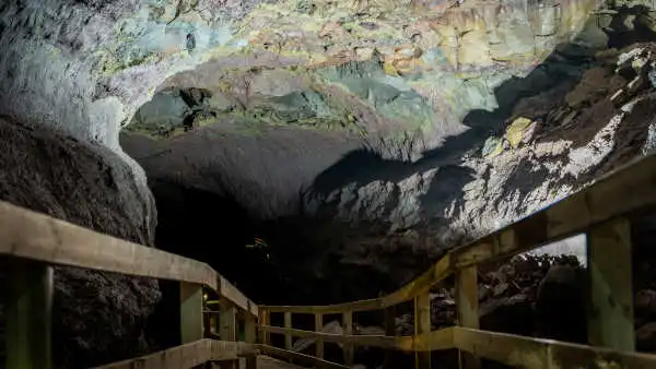 A colourful natural corridor of lava rock, with a wooden path at its bottom