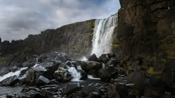 A small waterfall, falling down a natural wall onto a pile of rocks