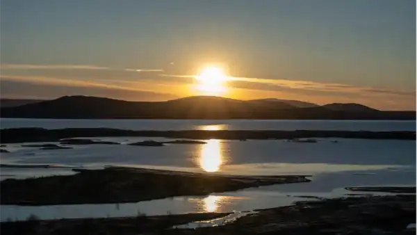 Sunrise over a lake, with mountains in the background