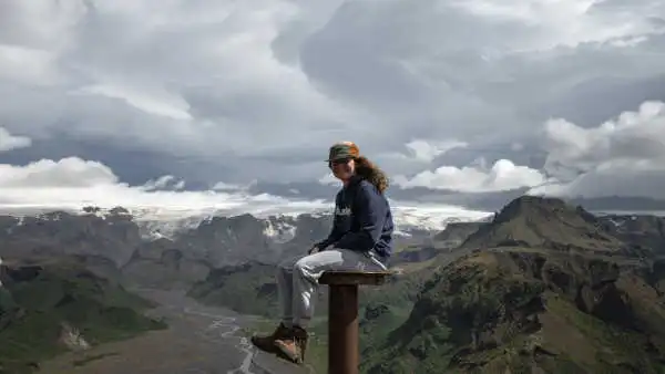 A young girl sits and smiles on a orientation table at the top of a mountain