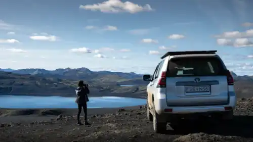 A blue mercedes V-Class van in front of a lake