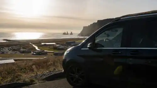 A blue mercedes V-Class van in front of a lake